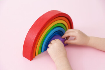 Naklejka na ściany i meble Little girl playing with toy rainbow on pink background, closeup