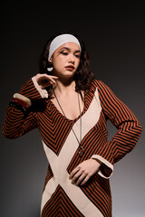 Obraz premium Stylish young woman showcases bold striped dress in modern studio setting