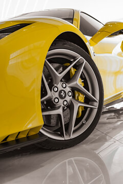 Yellow Ferrari F8 Tributo front wheel close up, V8 supercar front end detail in bright showroom