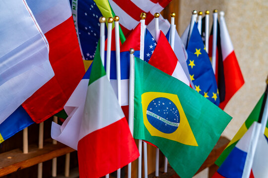 Small national flags on sticks, Brazil, Italy, European Union, Poland, international symbols for travel and tourism, colorful patriotic background, close-up of world flags at sports or cultural event.