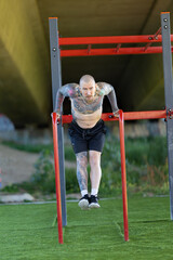 Obraz premium Strong man performing calisthenics dips on parallel bars