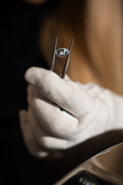 Gemologist inspects a diamond using tweezers and a loupe to evaluate clarity and cut quality.