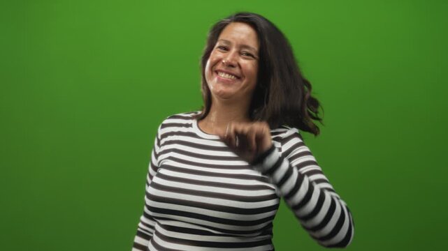 Woman forms l with hand on forehead in studio green screen wearing striped shirt, smiling and tilting head; playful teasing.