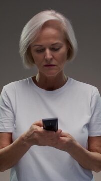Old woman hand holding tv remote control. Elderly female presses button of device and turns channel, switching surfing. Senior lady with grey hair turn off on television. Recreation and entertainment