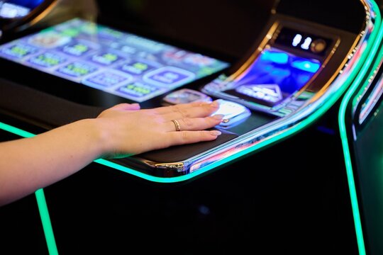 Close Up Female Hand Pressing Slot Machine Button in Luxury Casino Gambling Concept