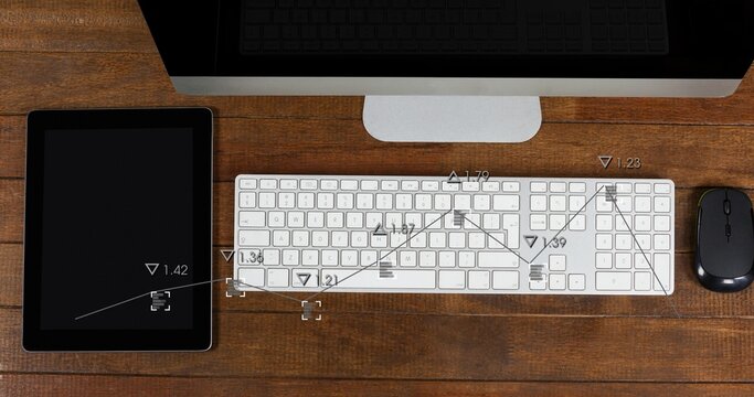 Displaying white computer keyboard centered on wood desk with monitor, tablet, mouse, data overlays