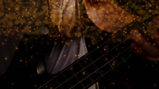 Male bassist moving left hand, plucking strings, sparking golden particles around neck during music