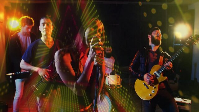 Female lead singer starting song, leaning into mic while radial dots overlaying band performance