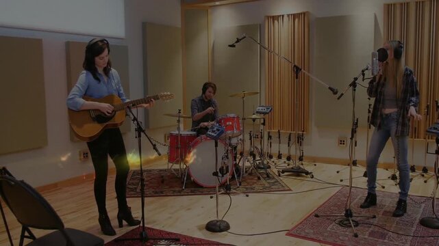 Acoustic guitar strumming drummer drumming singer singing tracking in studio while sparks over band