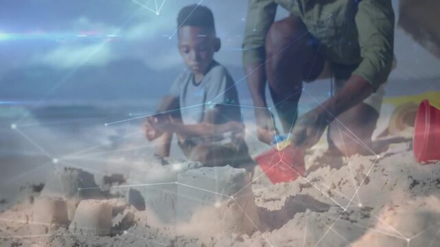 Dad scooping into red bucket triggers son shaping towers on beach, tech overlay aiding castle build