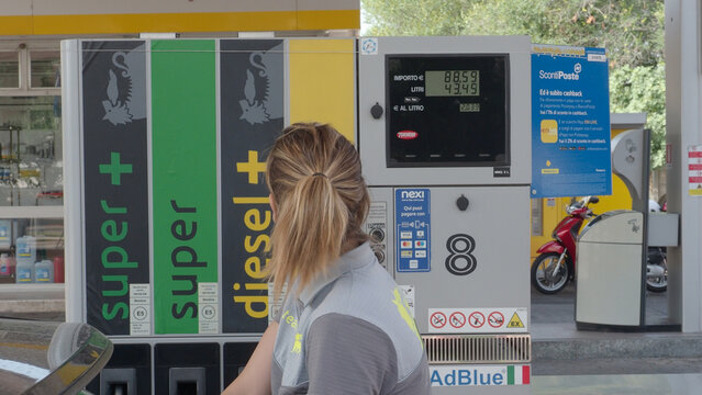 A woman observes the increasing cost of fuel displayed on a digital screen at a service station, highlighting economic concerns