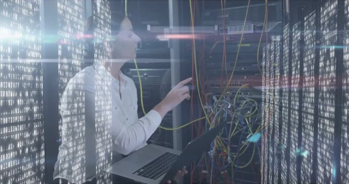Vertical video: Alerting tech in white shirt testing datacenter ports with yellow cable, laptop