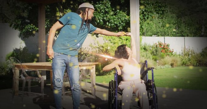Man extending arm, guiding woman in wheelchair during dance therapy, sparkles highlighting motion