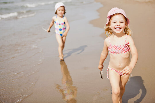 Two Young Girls Running and Laughing on the Beach.