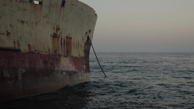 Rusty old shipwreck near the coastline on sunset