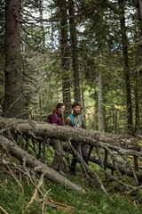 Obraz premium Couple in full trekking gear walking through a dense green forest trail.