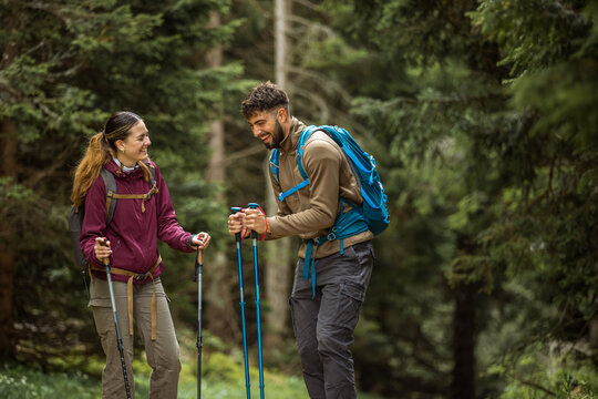 Rear view of a happy couple in hiking gear stopping to talk and laugh in the forest.