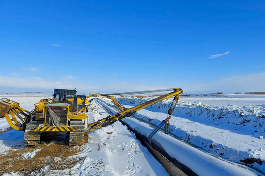 Laying pipelines in ditch with the help of pipelayer loaders, construction of oil pipelines and gas pipelines in remote areas.