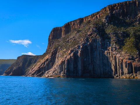 Cape Raoul seascape with rock platforms, towering cliffs, columns, blue sky, and the Tasman Sea in Tasmania, Australia