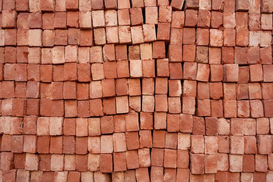 Stack of red bricks arranged end-on, close-up texture background for construction industry