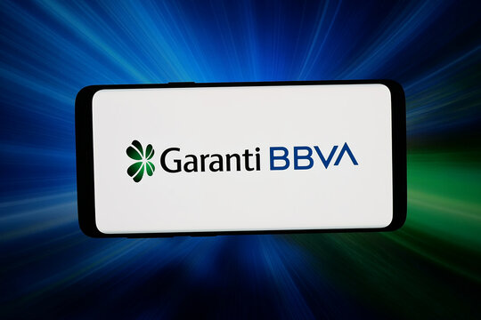Stuttgart, Germany - 03-26-2026: In this photo illustration, the logo of Turkish financial company Garanti BBVA is displayed on a smartphone in front of abstract background on computer screen.