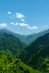Obraz premium Vertical landscape of lush green mountain valley and forest slopes. The vastness of the wilderness with distant hazy peaks and a communication tower visible on the ridge and vertical landscape.
