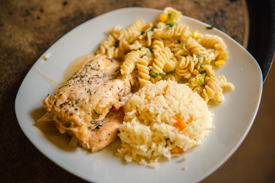 Grilled chicken served with pasta and creamy side, a hearty and delicious meal.