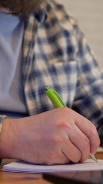 Man brainstorming at desk. Individual with light skin writing and planning at workplace desk. Caucasian man actively brainstorming and reviewing schedules while making notes at his office workspace
