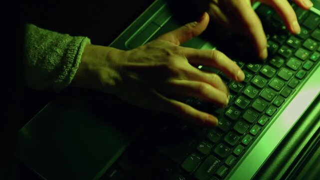 Business woman typing the fingers on keyboard. Laptop placed on a desk in dark work space. Low key shadow with green color art lighting. Closeup series of videos from different angles