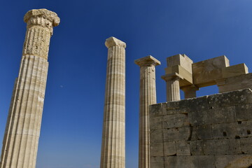 Lindos Acropolis, Lindos, Rhodes Island, Greece. The tall column and cornice of an archeological Roman-Greek temple site of Athena from the 4th century BC in Spring. © alagz