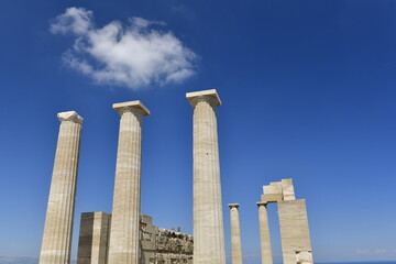 Lindos Acropolis, Lindos, Rhodes Island, Greece. The tall column and cornice of an archeological Roman-Greek temple site of Athena from the 4th century BC in Spring. © alagz