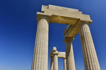 Lindos Acropolis, Lindos, Rhodes Island, Greece. The tall column and cornice of an archeological Roman-Greek temple site of Athena from the 4th century BC in Spring. © alagz