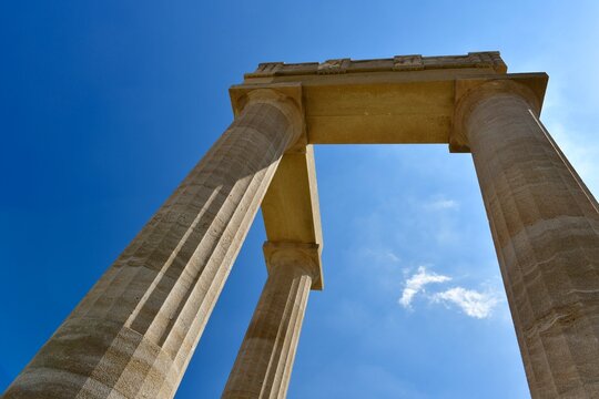 Lindos Acropolis, Lindos, Rhodes Island, Greece. The tall column and cornice of an archeological Roman-Greek temple site of Athena from the 4th century BC in Spring.