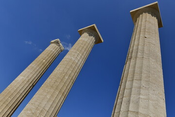 Lindos Acropolis, Lindos, Rhodes Island, Greece. The tall column and cornice of an archeological Roman-Greek temple site of Athena from the 4th century BC in Spring. © alagz