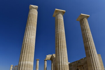 Lindos Acropolis, Lindos, Rhodes Island, Greece. The tall column and cornice of an archeological Roman-Greek temple site of Athena from the 4th century BC in Spring. © alagz
