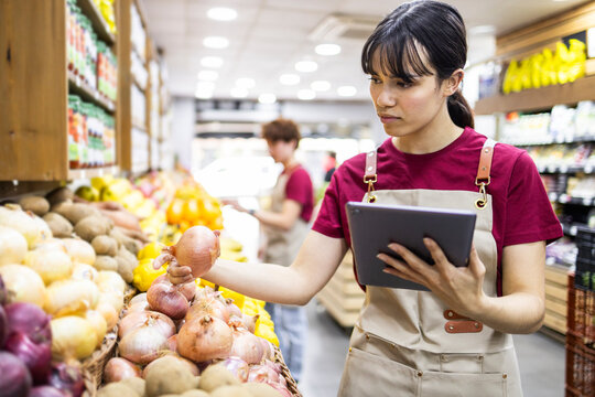 Shop assistant examining produce in a fruit store