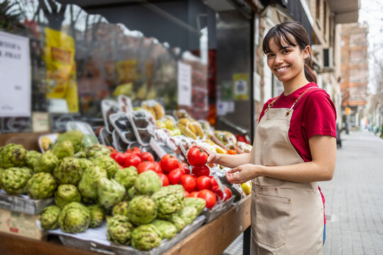 Shop assistant sorting fresh fruits at a grocery stand