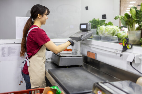 Shop assistant weighing produce in fruit store