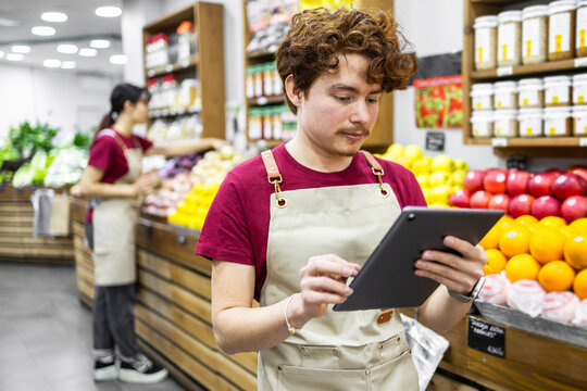 Shop assistant using tablet in a fruit store