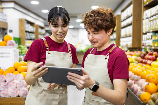 Shop assistants using tablet in a vibrant fruit store