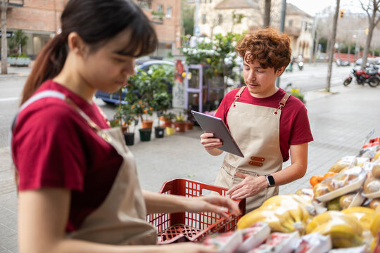 Shop assistants managing grocery fruit store inventory