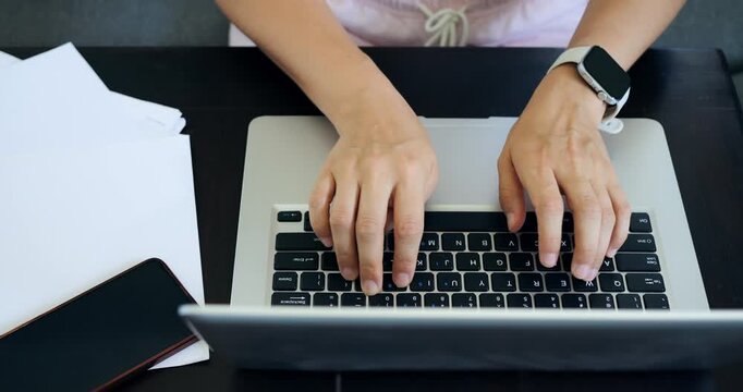 Female coder working. Young woman concentrating on programming while surrounded by papers and digital data. Female developer intensely working on code at her desk with supporting documents close by