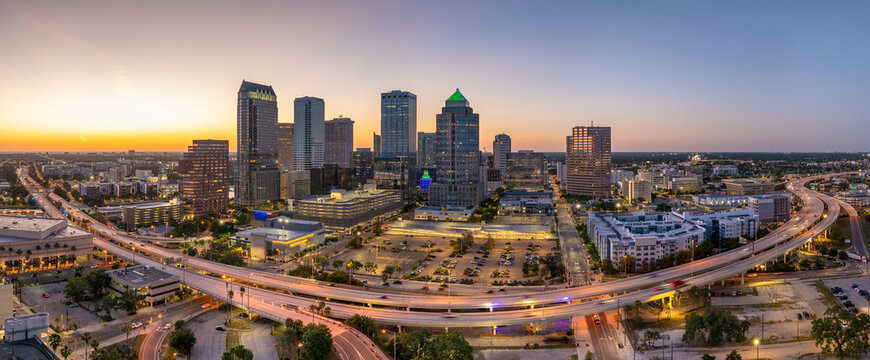 Tampa, Florida. Cars traffic driving on wide highway and high skyscraper buildings in downtown district. American city with business financial district at nightfall.