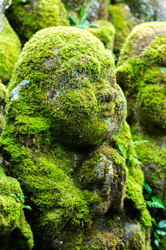 Close-up view of praying stone statue covered in moss at Otagi nenbutsu-ji temple in Arashiyama, Kyoto, Japan 