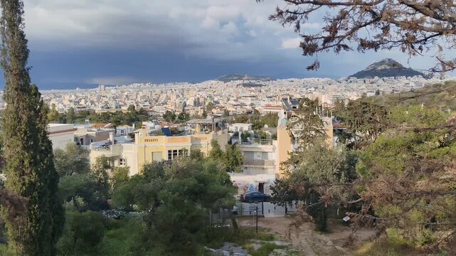 360 degree panoramic view of Athens from the Hill of the Nymphs. Scenic footage showing the vast urban landscape, the Acropolis, and Mount Lycabettus under a dramatic cloudy sky in the afternoon.