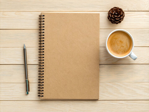 Kraft Spiral Notebook with Coffee Cup and Pen Flat Lay on Natural Wooden Surface