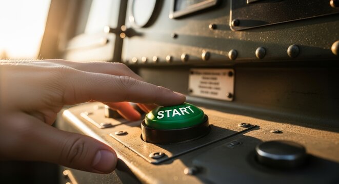 Hand pressing green start button on industrial control panel