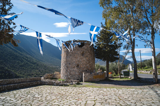 Historic stone tower of a former windmill in Leonidio, Greece, with Greek flags hanging on a string.