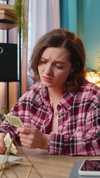 Caucasian young woman freelancer counting cash insufficient amount of money. Financial crisis. Bankruptcy. Poverty and destitution. Female girl businesswoman with laptop sitting at home office table.