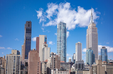 Obraz premium View of New York City skyline showcasing iconic Manhattan landmarks, buildings and skyscrapers on sunny day with clear blue sky.